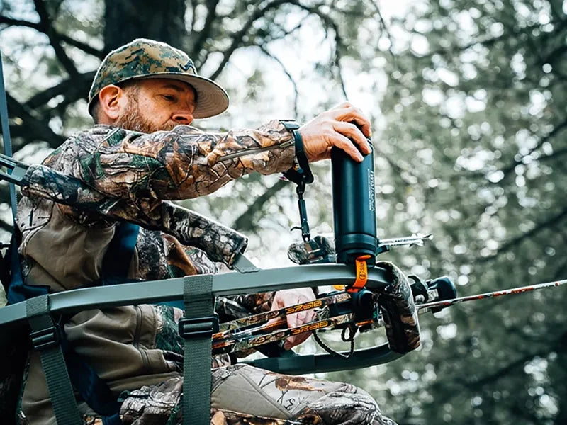 Bow hunter in a tree stand locking his TwistLock Canteen into the bar mount locking drink holder.