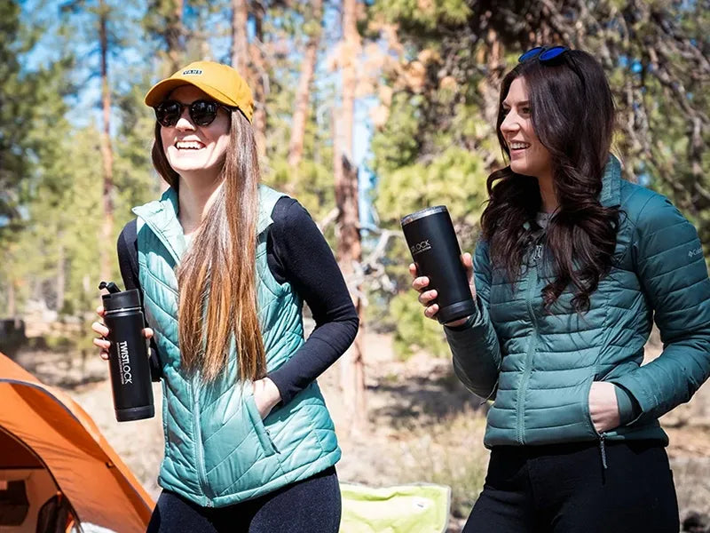 Two friends camping holding their insulated canteen and tumbler.