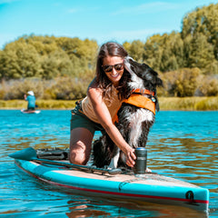 Insulated can cooler attached to SUP with a woman and dog on the board.