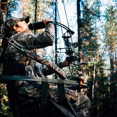 Hunter in tree stand drinking a from a canteen with his Bar Mount attached to the stand.