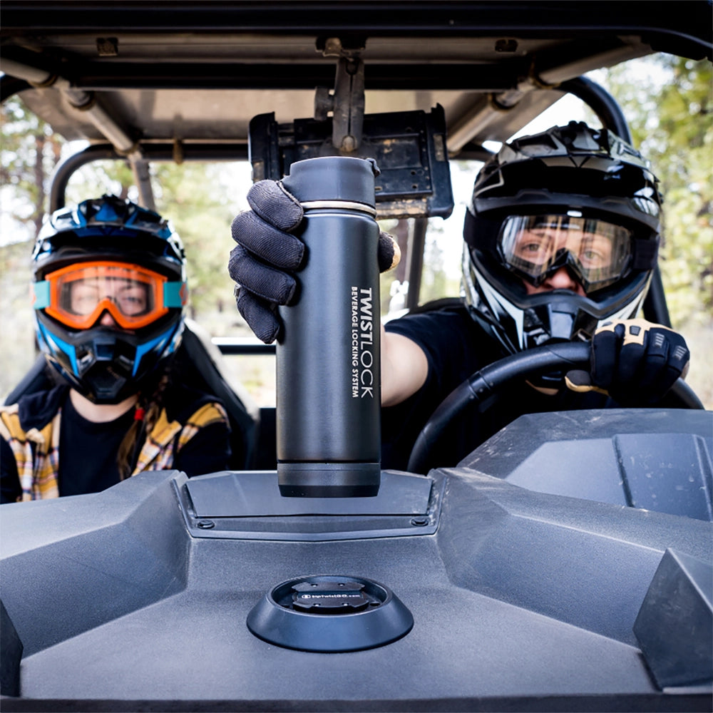 Two riders in a side by side with removable cup holder securing their canteen down.