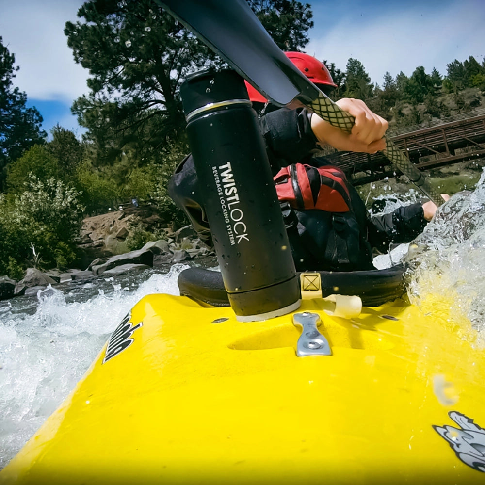 Whitewater kayaker with drinkware secured to his cup holder while paddling.