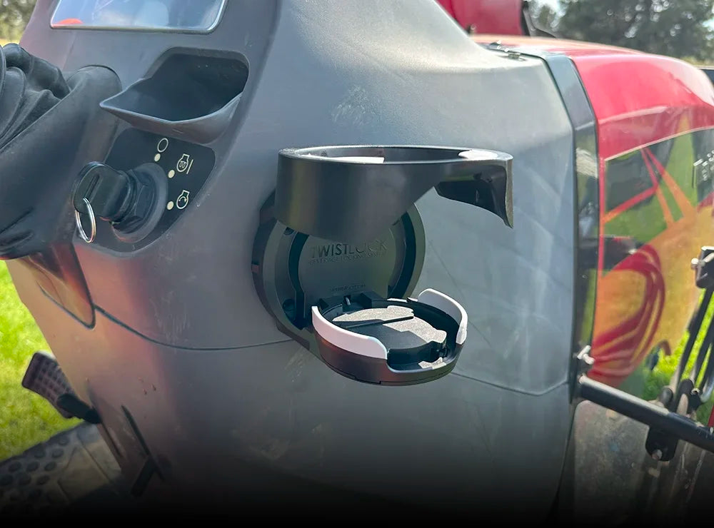 The TwistLock Vertical Mount Folding Cup Holder in the open position mounted to the side of a red tractor.