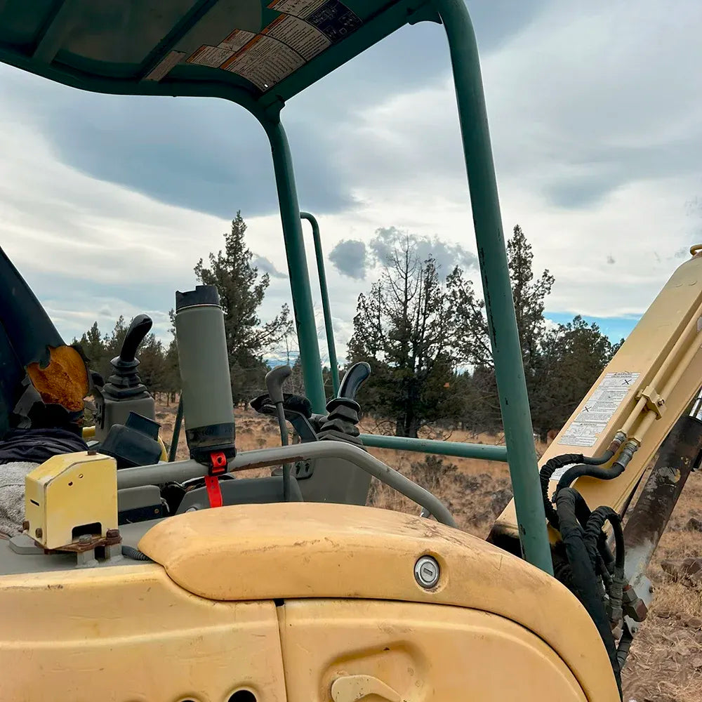 A Green TwistLock 20oz Coffee Canteen attached to the Bar Mount cup holder on a grab handle of an excavator.