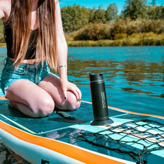 Woman sitting on a paddleboard with an attachable cup holder on the front with an insulated canteen secured into it.