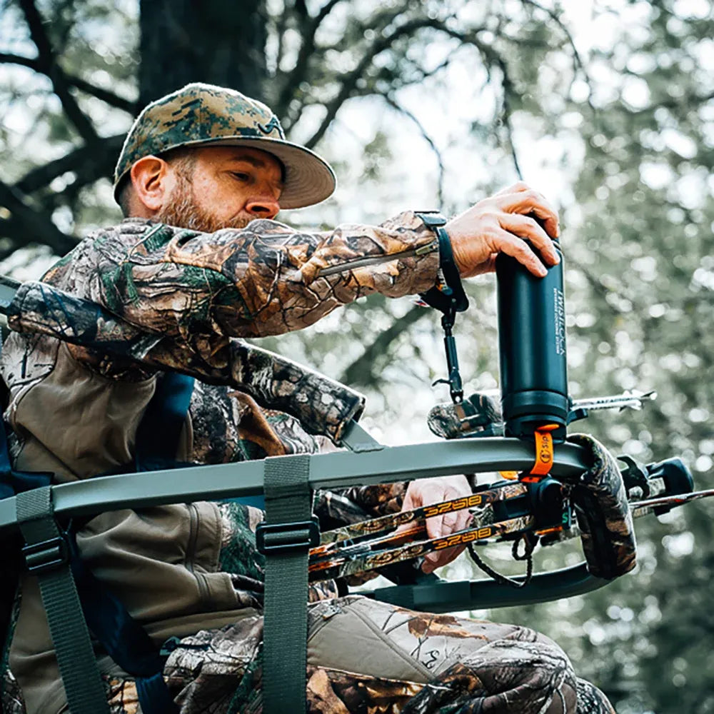 Hunter in tree stand with a bar mount locking cup holder attached to the stand. He is unlocking an insulated canteen from the mount.