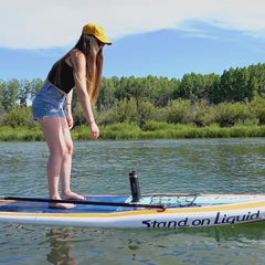 A woman on a paddle board reaching for her canteen, unlocking it, and locking it back into the attachable SUP cup holder.