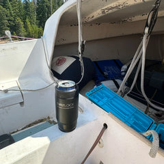 A sailboat with a secure cup holder attached to the centerboard cover. The cup holder has an insulated can cooler locked into it.