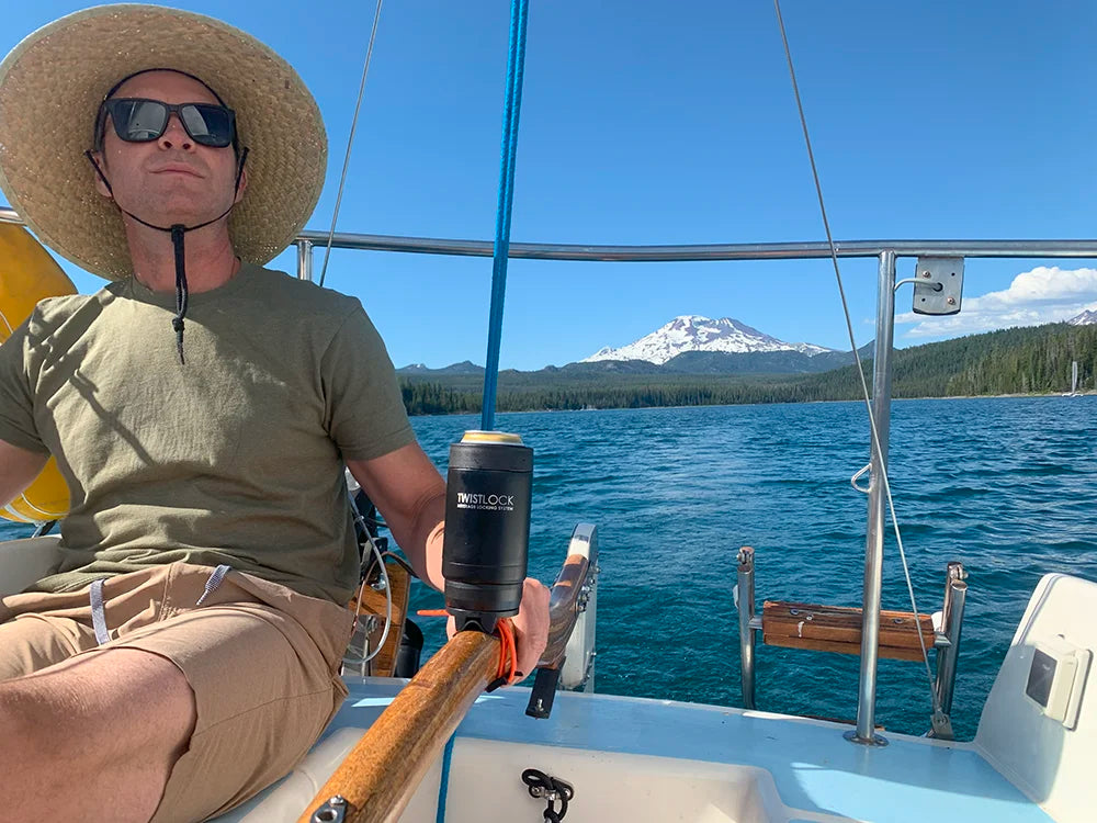 Sailboat locking cup holder attached to the tiller. An insulated can cooler is secured to it.