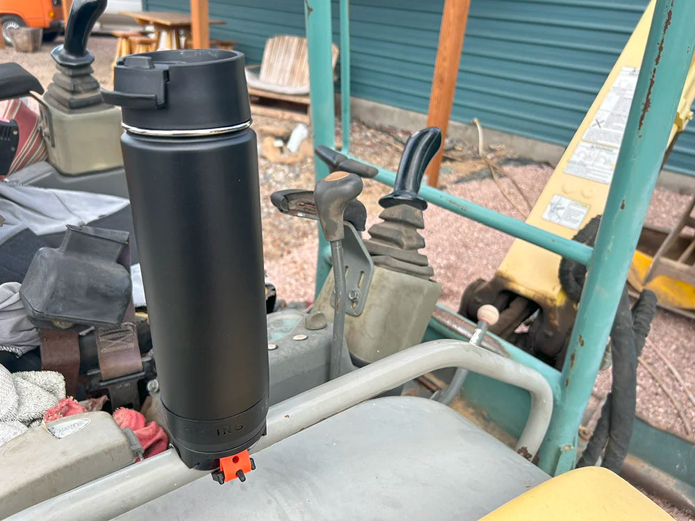 An attachable locking cup holder on an excavator with an insulated canteen secured in.